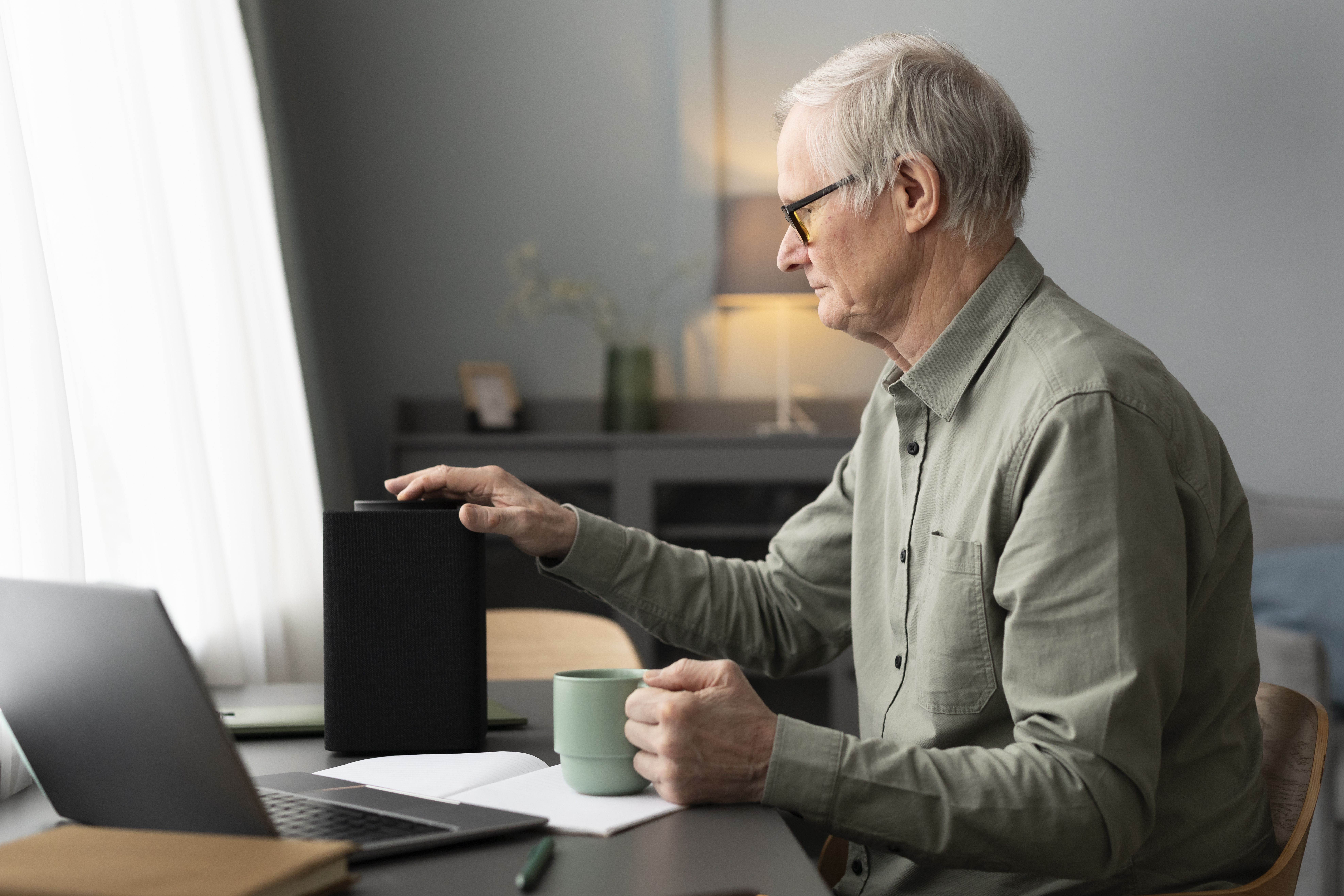 senior-man-sitting-desk-turning-speaker-living-room